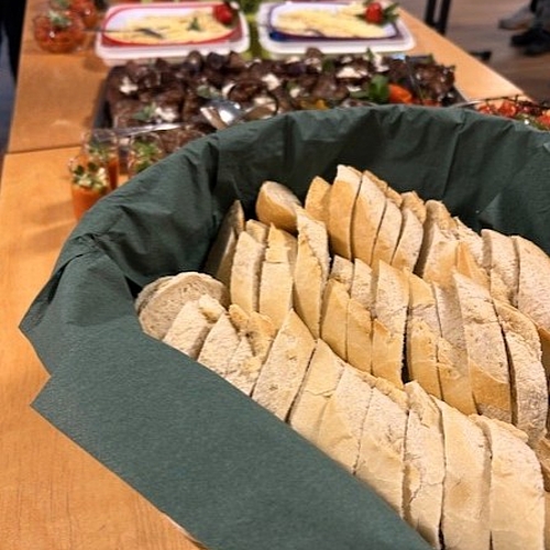 Tisch mit Brotscheiben, Tapas, Aufstrichen und kleinen Gläsern mit Speisen für Gäste einer Ausstellung.